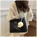 Detail of black leather tote bag featuring a silver metal chain and white plush octopus charm - With Plush Charm / Black