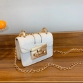 White mini crossbody bag with crocodile texture and gold chain strap on a wooden surface - White