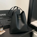 Minimalist black tote bag with gold lettering in a stylish urban lifestyle setting - Black