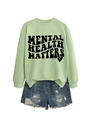 Detail view of mint green sweatshirt with Mental Health Matters text and ripped denim shorts - Olive Green (Black Font)