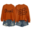 Detail view of orange sweatshirt with printed text and distressed denim shorts set - S / Black Font / Burnt Orange