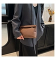 Detail of dark brown woven leather envelope clutch bag held by model in office setting - Brown