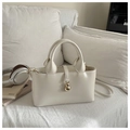 Bolso tipo cubo minimalista de cuero blanco crema con colgante dorado en el sofá - Blanco