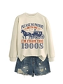 Close-up of beige sweatshirt with 1900s slogan and distressed denim shorts - Sand