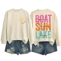Flat lay view of a beige sweatshirt showing Lake Days graphic and distressed denim shorts - Sand-Black Text Print