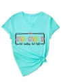 Dettaglio della t-shirt verde menta con scollo a V, stampa grafica e nodo sull'orlo - S / Verde Menta