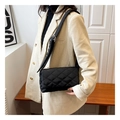 Detail of black quilted nylon shoulder bag with adjustable strap worn on a beige blazer - Black