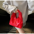 Elegant bright red handbag with a unique twisted handle design and soft leather texture - Red