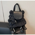 Detalle de la mochila de nailon plisado negro con solapa de cuero y bolsa con lazo decorativo - Negro