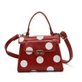 Red crossbody bag with large white polka dots, featuring a top handle and metal clasp - Red