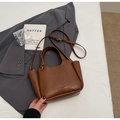 Sac seau rétro en cuir marron avec poignée et bandoulière réglable sur un lit - Brun Sans Pendentif