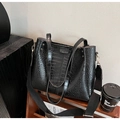 Detail of black crocodile texture tote bag with wide strap on wooden shelf display - Black