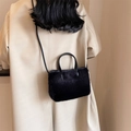 Sac à main en peluche noire avec bandoulière en cuir porté par un mannequin en manteau - Noir
