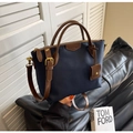 Dettaglio borsa a secchiello in nylon blu navy con manici in pelle marrone e finiture oro - Blu scuro