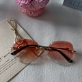 Close-up of rimless oval sunglasses with diamond-cut pink gradient lenses and gold temples - Pink