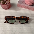 Detalle de gafas de sol rectangulares retro en carey con lentes verdes sobre fondo blanco - Montura Carey Lentes Verdes