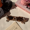 Detail van een rechthoekige cat-eye zonnebril met schildpadmotief op stenen ondergrond - Melkkoe Patroon
