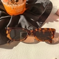 Close-up van luipaardprint cat-eye zonnebril met donkere UV-glazen op getextureerd vlak - Luipaardprint