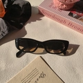 Detail van vintage cat-eye zonnebril met glanzend zwart montuur en amberkleurige glazen - Donkerbruin