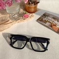 Detail of black square glasses frame with golden metal hinges on a beige surface - Black & White