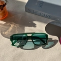 Détail de lunettes aviateur vert foncé translucides sur une surface texturée et élégante - Vert
