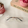 Detalle de gafas octogonales sin montura de oro rosa sobre fondo minimalista - Dorado