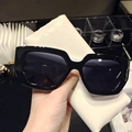 Detail of stylish rectangle sunglasses held against a white leather glasses case - Black Frame White Temples