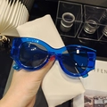 Detalle de gafas de sol retro con montura azul eléctrico y una funda de cuero blanco suave - Azul eléctrico