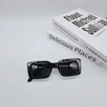 Close-up of black rectangular sunglasses with premium thick frames on white books - Bright Black