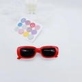 Detail view of red square retro children's sunglasses with dark lenses on a white backdrop - Red