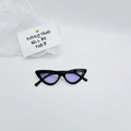 Close-up van de retro cat-eye zonnebril met zwart montuur en paarse transparante glazen - Zwart frame paarse glazen