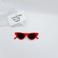 Detail of red cat-eye sunglasses for kids with dark lenses and minimalist paper background - Red