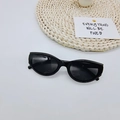 Occhiali da sole neri ovali piccoli con design retrò cat-eye su un tappetino beige - Nero
