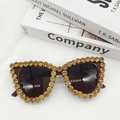 Macro detail of cat-eye sunglasses featuring luxury amber rhinestones on a white fabric - Leopard Print