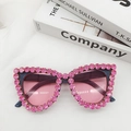 Détail de lunettes œil de chat avec strass roses et verres dégradés sur des livres - Rose