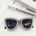 Macro detail of oversized black sunglasses with luxury crystal rhinestones on white fabric - Black