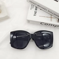 Flat lay of black oversized square sunglasses on white fabric with minimalist book decor - Black