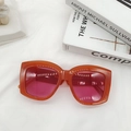 Detail of orange square frame sunglasses with purple lenses on white fabric - Orange Red