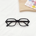Close-up of black square eyeglass frames with gold accents on a wooden tray - Black Frame Clear Lenses