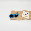 Close-up of blue parrot-shaped kids sunglasses with decorative wings and colorful feathers - Blue