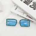 Detail of blue rhinestone rectangular sunglasses with crystal frames on a clean white fabric - Transparent Blue