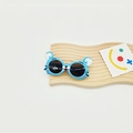 Détail de lunettes de soleil bleues en forme de souris posées sur un plateau en bois - Bleu