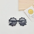 Détail de lunettes de soleil enfant en forme de fleur noire avec verres UV sur fond neutre - Noir