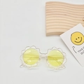 Detail shot of flower-shaped kids' sunglasses with yellow lenses on a decorative white background - Transparent Yellow