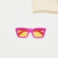 Vue à plat de lunettes de soleil carrées roses avec verres jaunes sur fond texturé blanc - Rose rouge