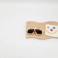 Détail de lunettes de soleil enfant beiges en forme d'ours sur un support en bois déco - Beige