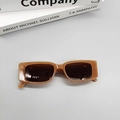 Detail view of rectangular caramel translucent frame sunglasses with dark lenses on books - Milk Tea