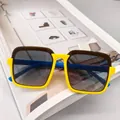 Detailed view of yellow and blue kids square sunglasses on a book background - Yellow