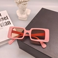Primer plano de gafas de sol rectangulares rosas en un soporte de exhibición negro - Rosa