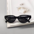 Close-up of black cat-eye sunglasses on a magazine with high-quality frame details - Bright Black / Gray